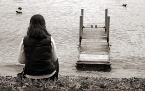 Frau sitzt einsam am See und versucht ihren Ex zu vergessen.