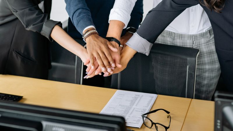 Teammitglieder legen Hände übereinander als Symbol für Zusammenhalt und Mission von Love Repair
