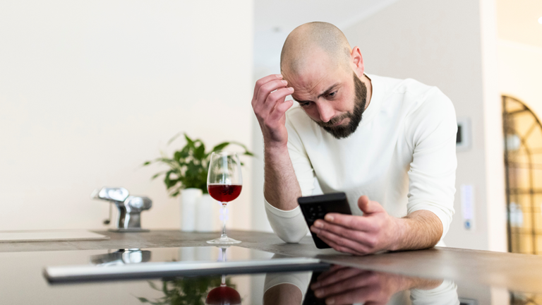 Florian Pohl – Wie Männer eine Frau vermissen Beziehungscoach Florian Pohl schaut nachdenklich aufs Handy – typische Situation, wie Männer eine Frau vermissen